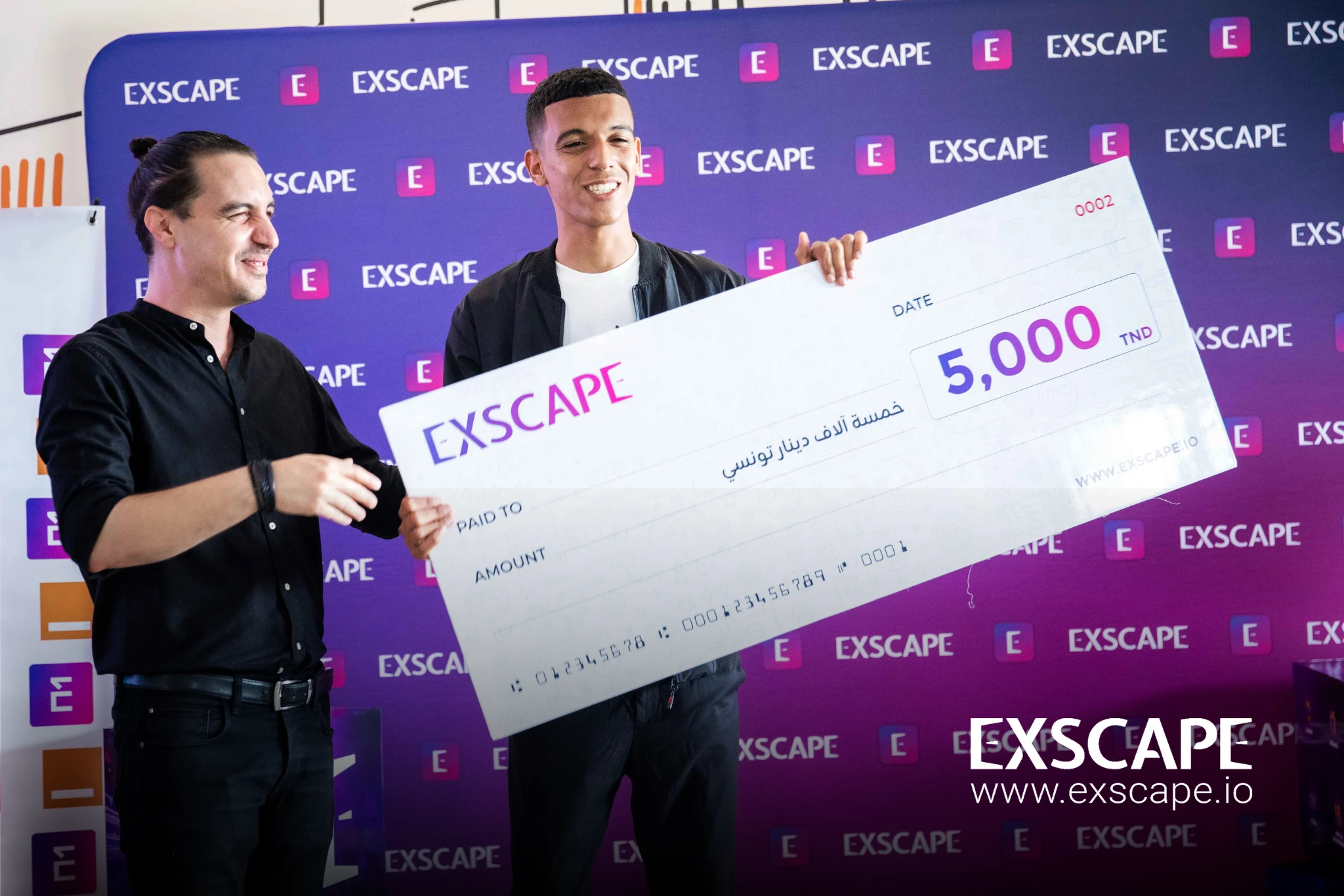 a winner is handed his check ands looks on at the crowd joyfully